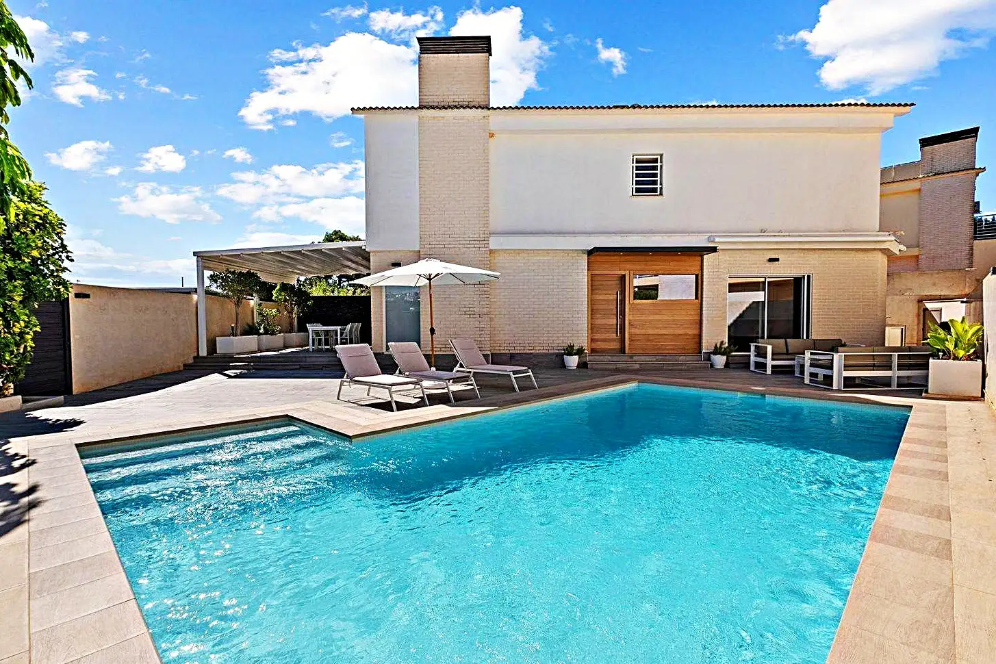 Piscina de obra con solárium y porche de madera en una villa de Tarragona